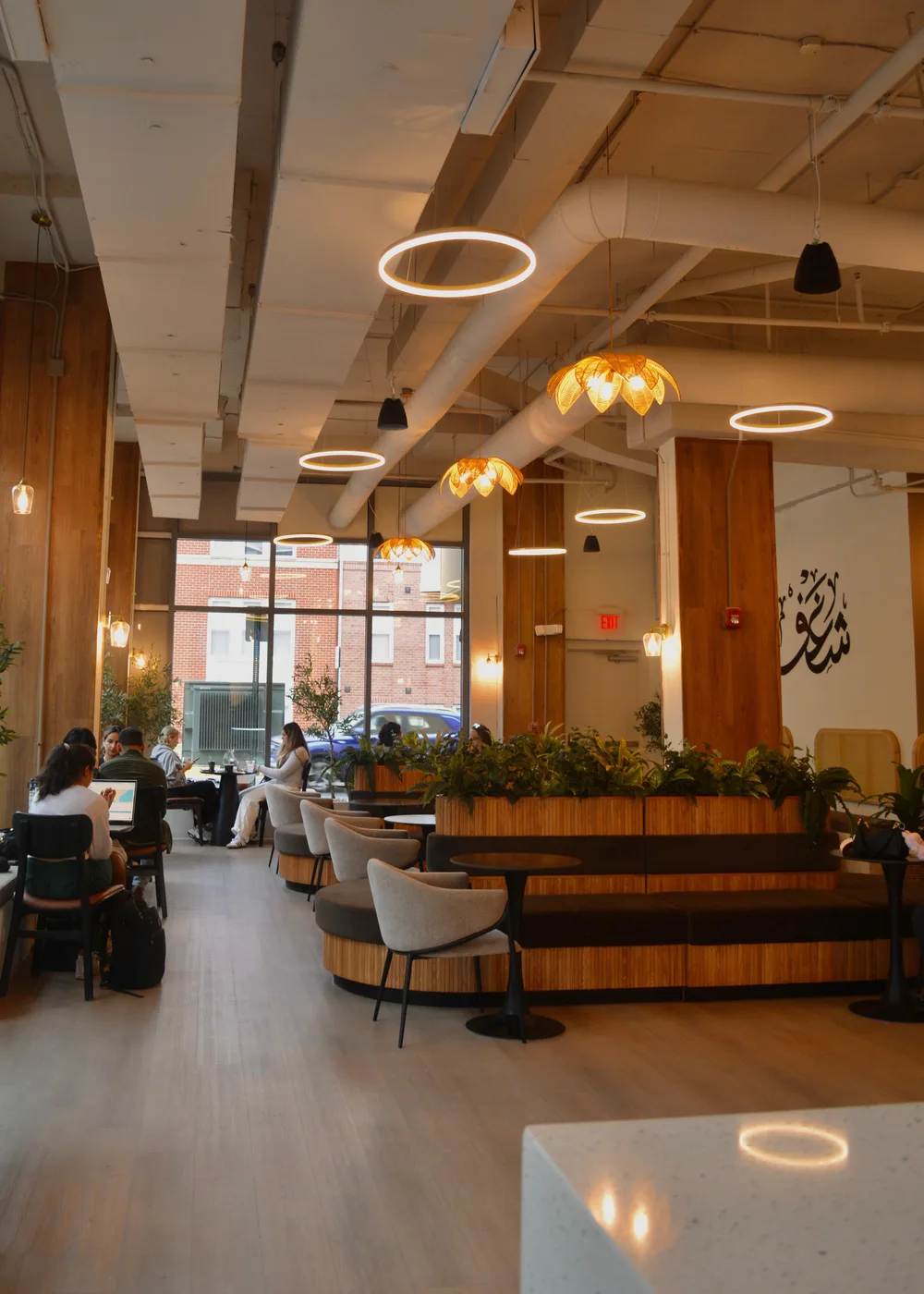 Guests seated among plants and warm pendant lights inside Shaghf Cafe